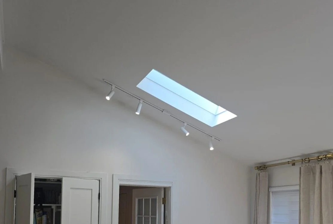 Track lights installed beside a skylight